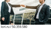close up businessman businesswoman standing front building bumping fist. Стоковое фото, агентство Ingram Publishing / Фотобанк Лори