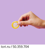 OLYMPUS DIGITAL CAMERA. close up woman holding unwrapped yellow condom. Стоковое фото, агентство Ingram Publishing / Фотобанк Лори