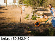 mother riding her daughters wheel barrow. Стоковое фото, агентство Ingram Publishing / Фотобанк Лори