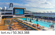 Tokyo, Japan - Oct 2 2024, panoramic view of the public outdoor pool on the upper deck of the MSC Belissima cruise ship, with people relaxing on sun loungers, at daytime, Tokyo, Japan. Редакционное фото, фотограф Сергей Богомяко / Фотобанк Лори