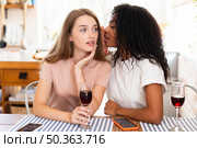 woman whispering secret her friends while having wine. Стоковое фото, агентство Ingram Publishing / Фотобанк Лори