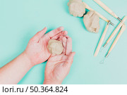 overhead view kneaded dough man s hand with sculpting tools mint green backdrop. Стоковое фото, агентство Ingram Publishing / Фотобанк Лори