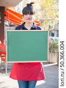 female entrepreneur holding blank green menu board outdoors caf. Стоковое фото, агентство Ingram Publishing / Фотобанк Лори