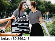 hand holding clapperboard front loving mime couple. Стоковое фото, агентство Ingram Publishing / Фотобанк Лори