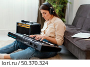 side view female musician with headphones playing piano keyboard. Стоковое фото, агентство Ingram Publishing / Фотобанк Лори