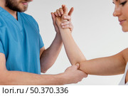 side view male osteopathic therapist checking female patient s elbow joint. Стоковое фото, агентство Ingram Publishing / Фотобанк Лори