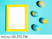 colourful easter eggs with blank frame blue table. Стоковое фото, агентство Ingram Publishing / Фотобанк Лори