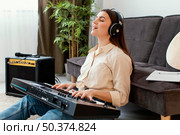 side view female musician singing playing piano keyboard. Стоковое фото, агентство Ingram Publishing / Фотобанк Лори