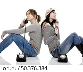 Two young women talking with old telephones - Isolated on white. Стоковое фото, агентство Ingram Publishing / Фотобанк Лори