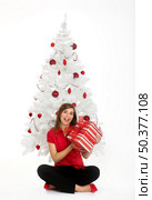 Beautiful happy woman near a white Christmas tree holding Christmas presents. Стоковое фото, агентство Ingram Publishing / Фотобанк Лори