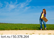 Young woman hitch hiking on a beautiful green meadow. Стоковое фото, агентство Ingram Publishing / Фотобанк Лори