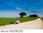 Young woman hitch hiking on a beautiful green meadow. Стоковое фото, агентство Ingram Publishing / Фотобанк Лори