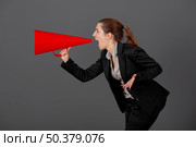 Business young woman speaking to a megaphone, over a grey background. Стоковое фото, агентство Ingram Publishing / Фотобанк Лори