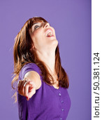 Beautiful and happy young woman pointing to you, over a violete background. Стоковое фото, агентство Ingram Publishing / Фотобанк Лори