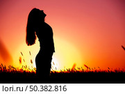 Silhouette of a young woman relaxing on a beautiful sunset of a summer day. Стоковое фото, агентство Ingram Publishing / Фотобанк Лори
