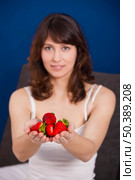 Beautiful and happy young woman holding strawberries with both hands. Стоковое фото, агентство Ingram Publishing / Фотобанк Лори
