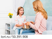 daughter giving gift box mom sitting couch. Стоковое фото, агентство Ingram Publishing / Фотобанк Лори