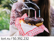 girl holding chocolate donut with extinguish candles. Стоковое фото, агентство Ingram Publishing / Фотобанк Лори