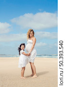 Beautiful pregnant woman and her little daughter on the beach. Стоковое фото, агентство Ingram Publishing / Фотобанк Лори