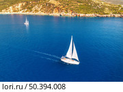 Aerial view of beautiful yachts. Boats on the sea at sunset in summer. Lefkada island, Greece. Top view of luxury yachts, sailboats, clear blue water, sky, mountain and green trees. Travel. Yachting. Стоковое фото, агентство Ingram Publishing / Фотобанк Лори