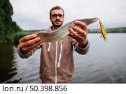 man showing freshly caught fish with lure hook. Стоковое фото, агентство Ingram Publishing / Фотобанк Лори