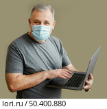 bearded man with surgical mask holding laptop. Стоковое фото, агентство Ingram Publishing / Фотобанк Лори
