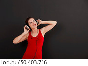 Happy woman over a black background listen music with headphones. Стоковое фото, агентство Ingram Publishing / Фотобанк Лори