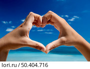 Female hand making a heart shape against a beautiful blue sky. Стоковое фото, агентство Ingram Publishing / Фотобанк Лори
