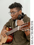 handsome male musician home playing guitar using headphones. Стоковое фото, агентство Ingram Publishing / Фотобанк Лори