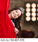 smiling girl peeking red curtain backstage. Стоковое фото, агентство Ingram Publishing / Фотобанк Лори