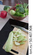 Vertical slow-motion footage of slices of sliced zucchini are on the cutting board on the kitchen table, a kitchen knife, plate with broccoli, green onion, red radish, lettuce, pomegranate. Стоковое видео, видеограф Vladimir Drozdin / Фотобанк Лори