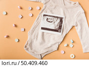 many mint candies with sonography picture baby onesie orange backdrop. Стоковое фото, агентство Ingram Publishing / Фотобанк Лори