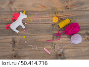 rag unicorn horse with yarn pink purple spool with thread button wooden desk. Стоковое фото, агентство Ingram Publishing / Фотобанк Лори