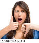 Beautiful woman confused making thumbs up and down. Up and Down. Стоковое фото, агентство Ingram Publishing / Фотобанк Лори