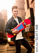 Studio portrait of a young man posing with a skateboard on street of New York. Стоковое фото, агентство Ingram Publishing / Фотобанк Лори