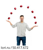 Happy young man juggling with apples on a white background . Стоковое фото, агентство Ingram Publishing / Фотобанк Лори