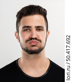 Studio portrait of a handsome young man with a bored expresion. Стоковое фото, агентство Ingram Publishing / Фотобанк Лори