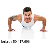 Athletic young man smiling and making pushups, isolated over a white background. Стоковое фото, агентство Ingram Publishing / Фотобанк Лори