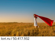 Young beautiful woman running while holding a red tissue. Стоковое фото, агентство Ingram Publishing / Фотобанк Лори