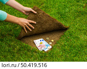 Finances concept, hands hiding money under the grass. Стоковое фото, агентство Ingram Publishing / Фотобанк Лори