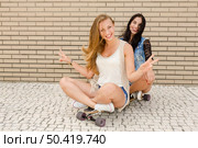 Two beautiful and young girlfriends having fun with a skateboard. Стоковое фото, агентство Ingram Publishing / Фотобанк Лори