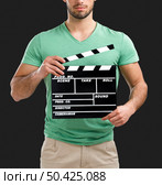 Portrait of handsome young man holding a clapboard, isolated on gray background. Стоковое фото, агентство Ingram Publishing / Фотобанк Лори