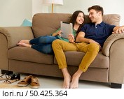 Young couple sitting on the sofa and watching something on a tablet. Стоковое фото, агентство Ingram Publishing / Фотобанк Лори