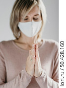 woman with medical mask praying home. Стоковое фото, агентство Ingram Publishing / Фотобанк Лори