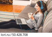 Beautiful woman working at home with a laptop while listen music and drinking coffee. Стоковое фото, агентство Ingram Publishing / Фотобанк Лори