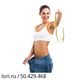 Woman with large jeans in dieting concept holding a measuring tape. Стоковое фото, агентство Ingram Publishing / Фотобанк Лори