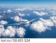Airplane is flying above the clouds at in summer. Landscape with passenger airplane, mountains, blue sky, sea. Aircraft is taking off. Business travel. Commercial plane. Aerial view. Transport. Jet. Стоковое фото, агентство Ingram Publishing / Фотобанк Лори