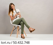 Beautiful woman sitting on a chair and texting a phone message. Стоковое фото, агентство Ingram Publishing / Фотобанк Лори