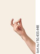 Female hand making finger snap gesture or holding invisible tiny object looking up isolated on cream or beige background. Soft grab action woman hand.. Finger snap woman hand with wrist on cream background. Стоковое фото, агентство Ingram Publishing / Фотобанк Лори