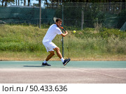 Tennis player hitting backhand at ball with racket on court. Стоковое фото, агентство Ingram Publishing / Фотобанк Лори